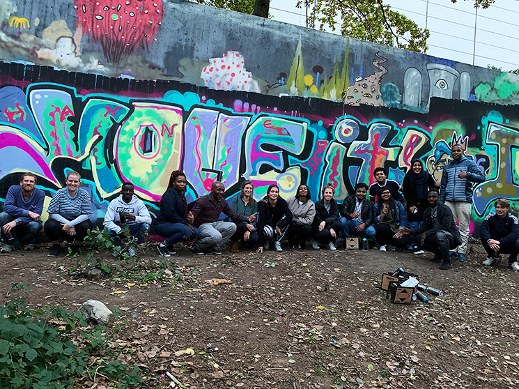 Die Gruppe posiert vor dem fertigen "Move it" Graffiti für ein Gruppenfoto.