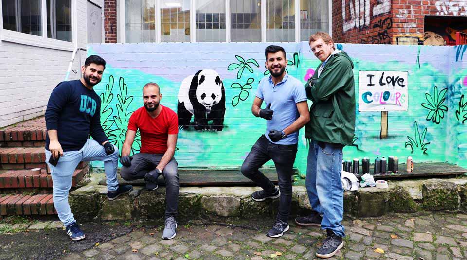 Drei Männer posieren vor dem Bild eines Pandabären für ein Foto.