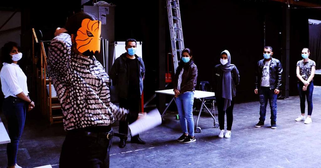 Die Gruppe trägt Corona Schutzmasken und die Gruppenleiterin trägt eine Tigermaske aus Papier.