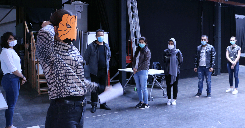 Die Gruppe trägt Corona Schutzmasken, die Gruppenleiterin hat eine Tigermaske aus Papier auf.