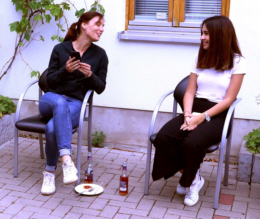 Zwei junge Frauen sind in ein Gespräch vertieft.