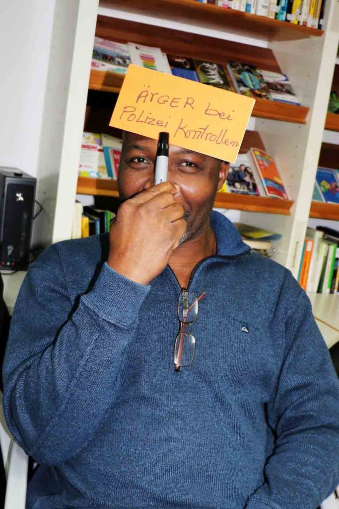 Ein Mann hält ein Schild mit der Aufschrift "Ärger bei der Polizeikontrolle" an seine Stirn.