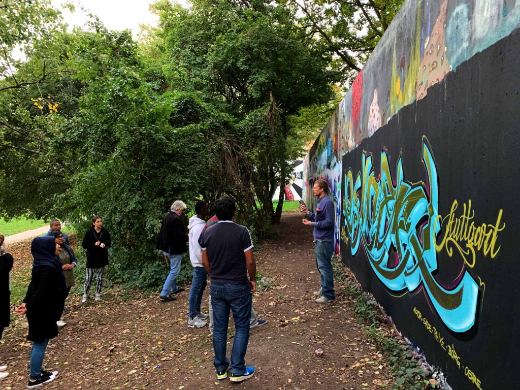 Der Gruppenleiter erklärt die Kunst des Graffitis der aufmerksam lauschenden Menge.